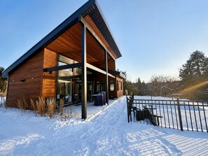 Un bâtiment moderne doté d’une façade en bois et de grandes fenêtres, entouré de neige.
