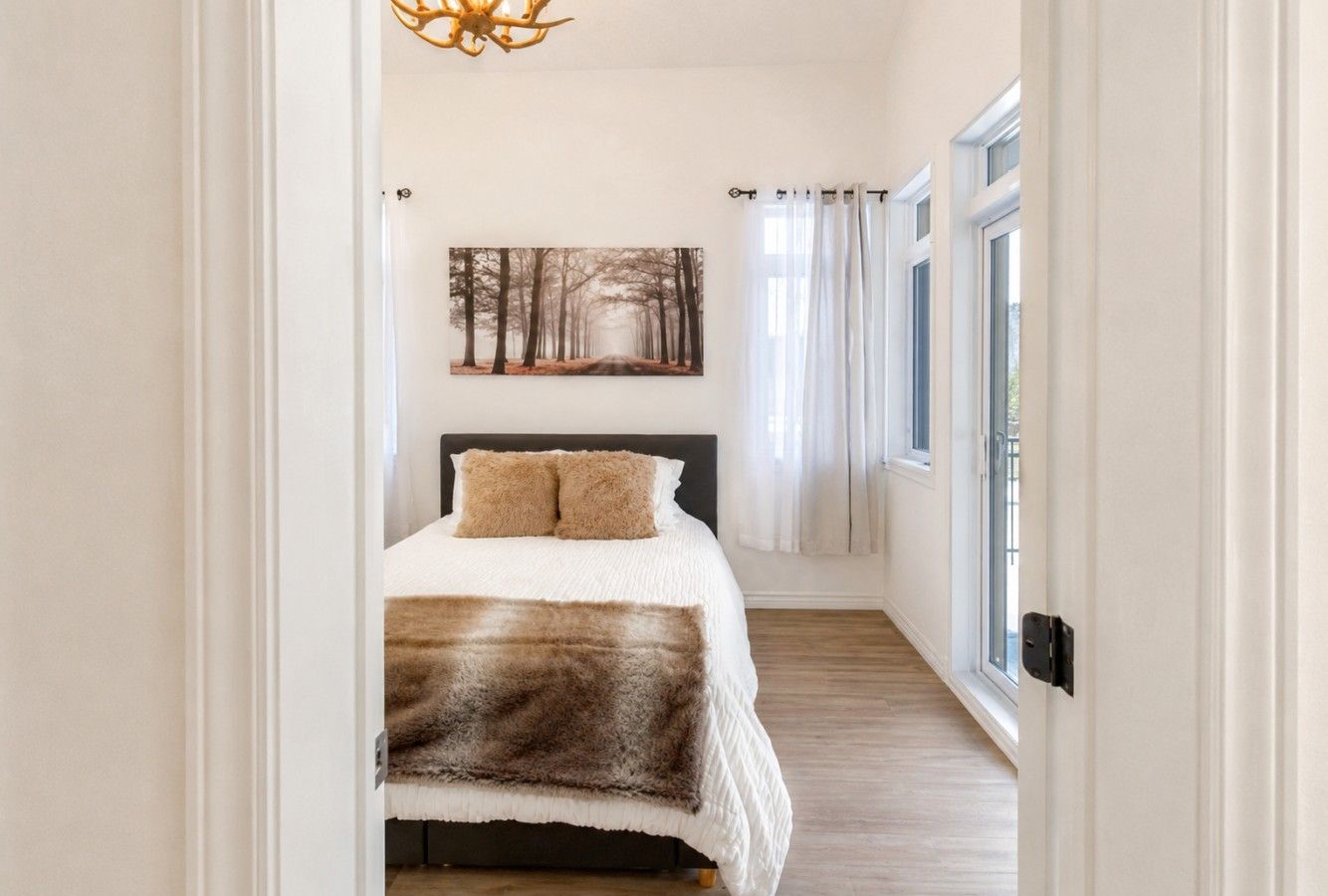 Ein Schlafzimmer mit einem Bett, einem Bild an der Wand und einem Fenster mit Vorhängen.