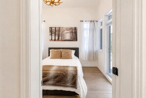Une chambre à coucher avec un lit, un tableau accroché au mur et une fenêtre avec des rideaux.