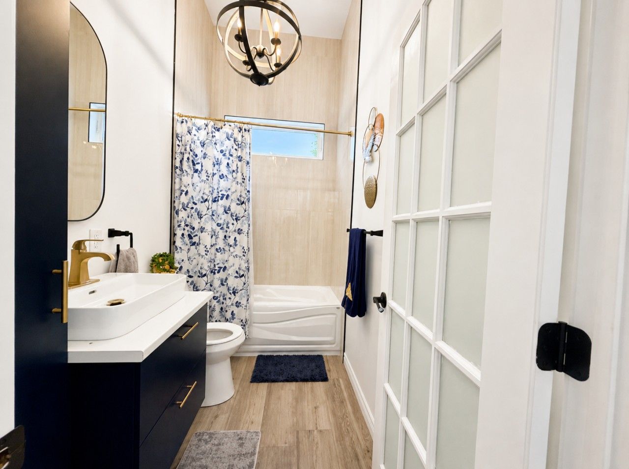A modern bathroom with a white sink, gold faucet, and a shower curtain with a floral pattern.