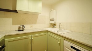 A kitchen with light green cabinets, a white countertop, a kettle, a sink, and a dishwasher. - BuddyRent - Borgo Pio's - San Pietro - 8 ospiti (Roma)