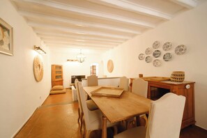Ein Essbereich mit Holztisch und -stühlen, einem Fernseher und dekorativen Tellern an der Wand.