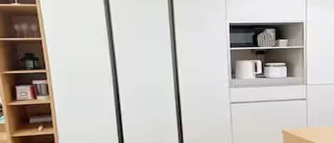 Una cocina moderna con armarios blancos, una estantería de madera y una encimera con utensilios de cocina.