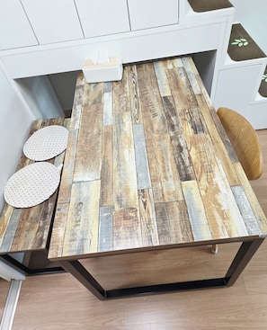 A table with a rustic wood plank design, a tissue box, and two patterned placemats. - Ansan Modern Style Duplex - Kitchen & Washer (Ansan-si)