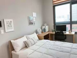 A neatly arranged hotel room with a bed, a desk, a chair, and a window. - Ansan Modern Style Duplex - Kitchen & Washer (Ansan-si)