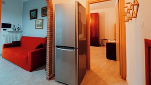 A modern kitchen with a built-in refrigerator, a red sofa, and a wooden door frame.
