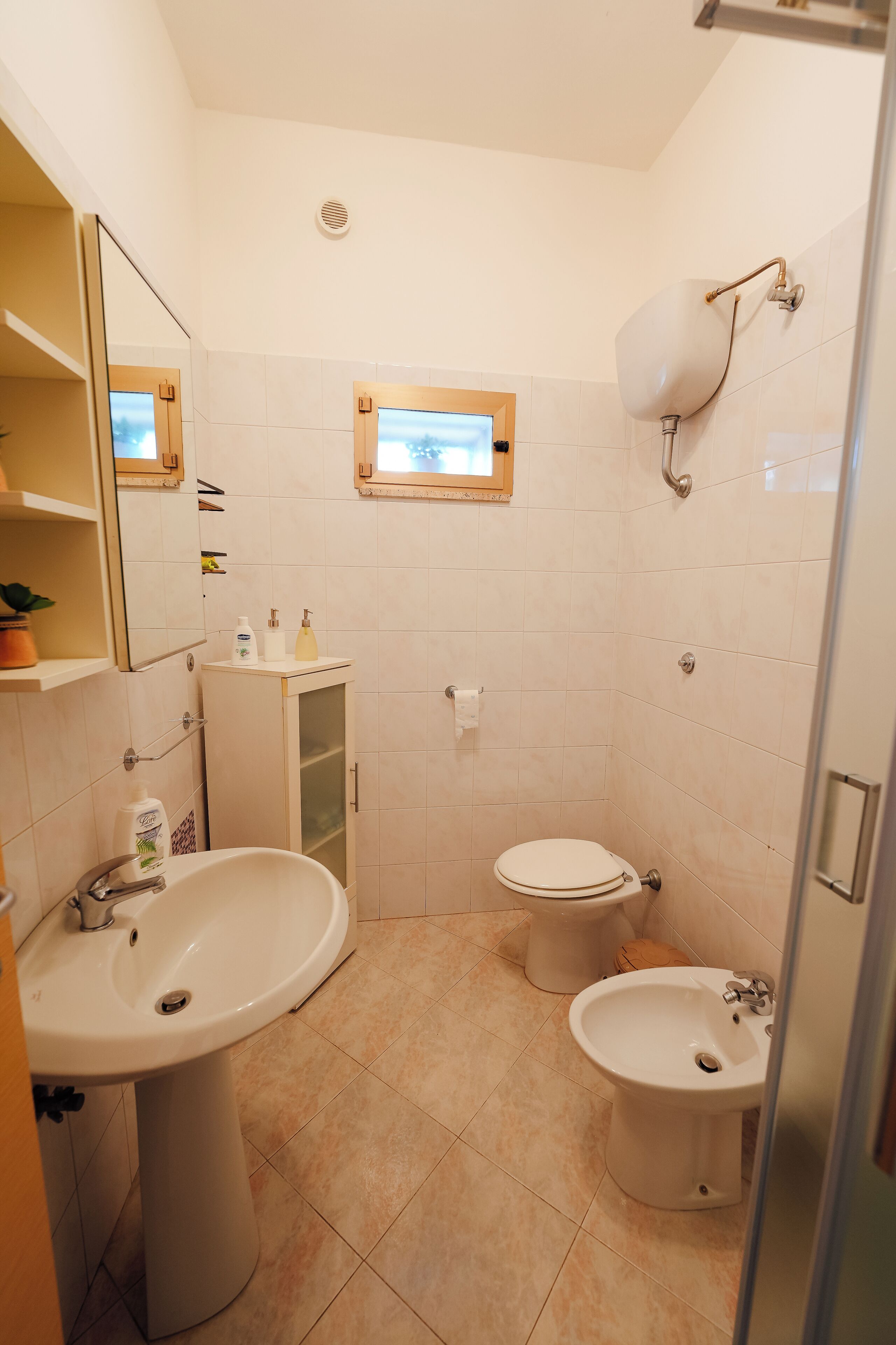 Ein Badezimmer mit Waschbecken, Toilette, Bidet und Spiegel.