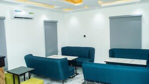 Une pièce moderne avec des canapés bleus, de petites tables et un plafond doté d’un éclairage encastré.