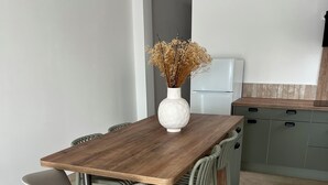 A modern kitchen with a wooden table, white chairs, and a vase with dried flowers. - Jules' keys (Gruissan)