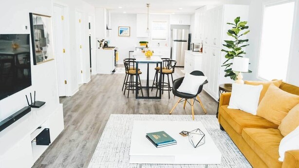 A modern living room with a sofa, coffee table, and a dining area with chairs and a table. - Downtown - 2 bed, 2 bath (Raleigh)