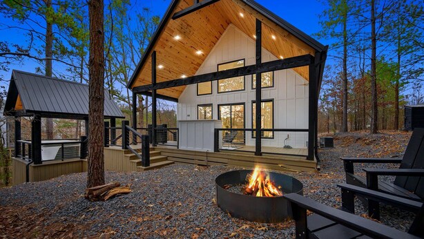A cabin with a covered deck, a fire pit, and outdoor seating. - Beautiful luxury romantic cabin: hot tub + outdoor swing + secluded+ creek (Broken Bow)
