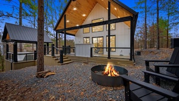 A cabin with a covered deck, a fire pit, and outdoor seating.