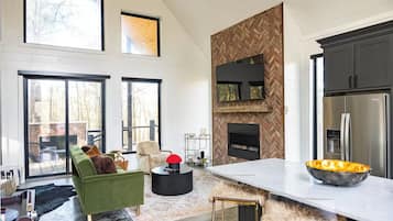 A spacious living area with a green sofa, a fireplace, and a large kitchen with modern appliances.