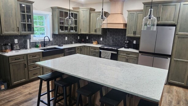 Una cocina moderna con una isla grande, taburetes de bar y electrodomésticos de acero inoxidable.
