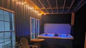 Una habitación acogedora con techo de madera, un jacuzzi, una pequeña mesa y una silla.