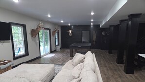 Una sala moderna con un amplio sofá modular, ciervos montados en la pared y vistas del exterior a través de grandes ventanales.