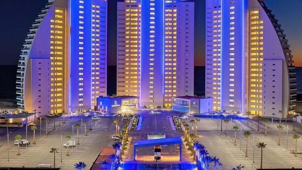 Ein modernes Hotel mit einem zentralen Atrium, mehreren Etagen und einem Parkplatz.
