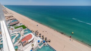 Ein Strandresort mit mehreren Schwimmbecken, Liegestühlen und einem Sandstrand.