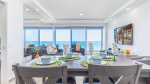 A dining area with a view of the ocean, a large window, and a modern interior design. - Splash Into Summer- Beachfront Condo @ the new Encantame Towers Resort (Puerto Peñasco)