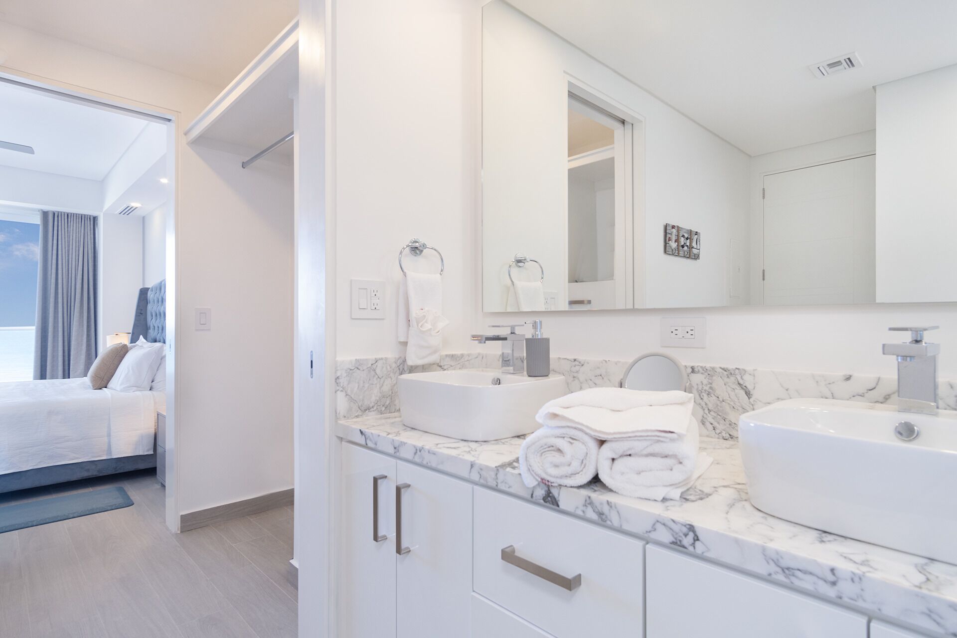 A modern hotel bathroom with two sinks, a large mirror, and a marble countertop.