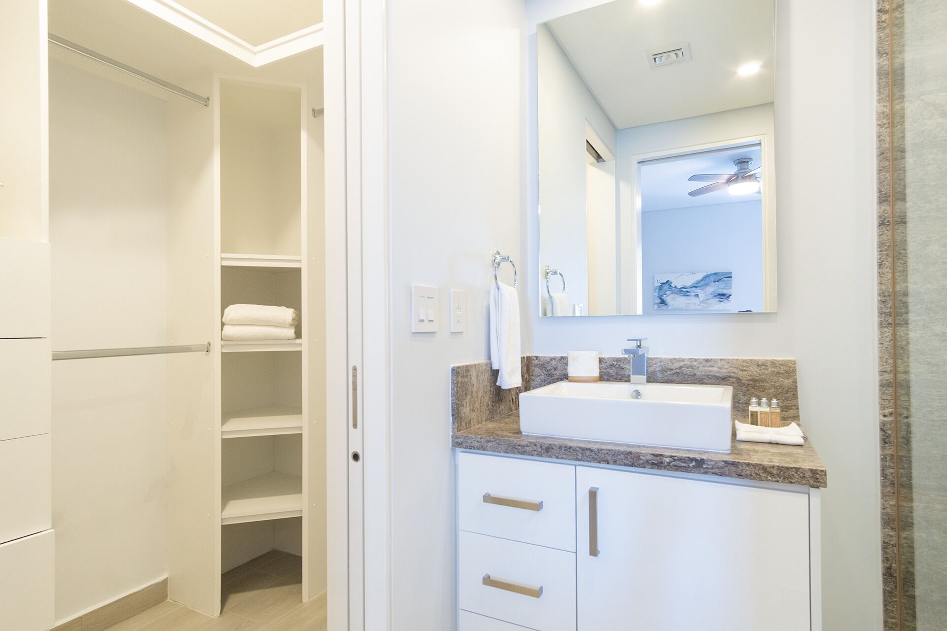 Un baño moderno con un tocador blanco, un espejo grande y una ducha empotrada.