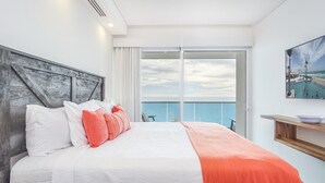 A modern hotel room with a large bed, a view of the sea, and a balcony with a pool. - Splendid Waterfront 2 Bedroom Velero 1804 Encantame Towers (Puerto Peñasco)