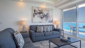 A modern living room with a grey sofa, two side tables with lamps, a coffee table, and a large abstract painting on the wall. - Splash in The New Lazy River and Sleep In Luxury Encantame Towers Velero 2104 (Puerto Peñasco)