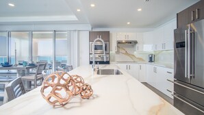 Cocina moderna con una isla grande, electrodomésticos de acero inoxidable y vistas al exterior.