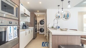 A modern kitchen with stainless steel appliances, a central island, and a dining area with a view.