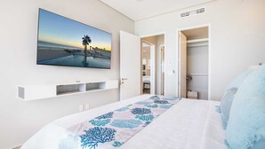Un dormitorio con cama, televisión montada en la pared y armario.