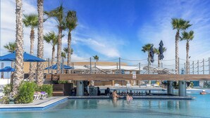 A pool area with palm trees, lounge chairs, and umbrellas. - Impressive & Beautiful 3 Bedroom Unit Ocean Front Encantame Velero-2301 (Puerto Peñasco)