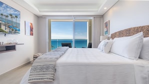 A hotel room with a large bed, a view of the sea, a balcony, and a painting on the wall. - Amazing two Bedroom Beach Front Condo W405 (Puerto Peñasco)