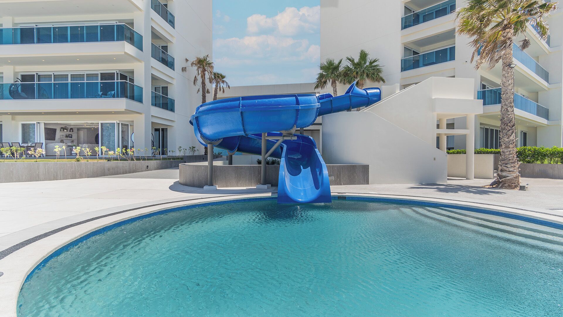 Un hotel moderno con una piscina grande y un tobogán de agua azul.