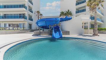 Un hotel moderno con una piscina grande y un tobogán de agua azul.