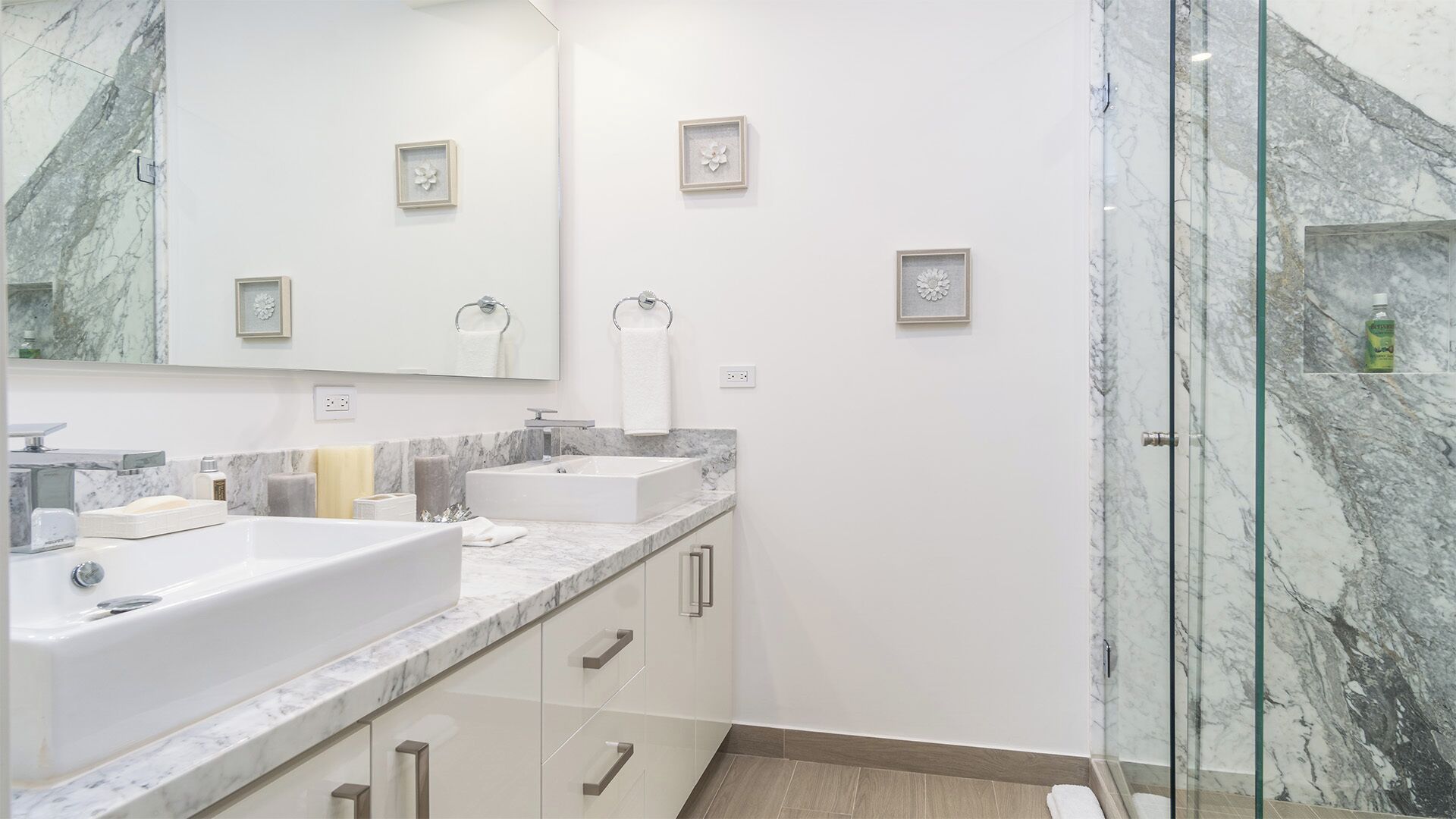 Un baño moderno con dos lavabos, un espejo grande y cabina de ducha de vidrio.