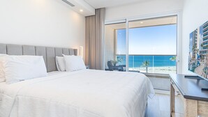A hotel room with a large bed, a view of the beach, and a balcony with a pool. - Encantame Towers Viento 304 (Puerto Peñasco)