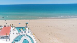 A beach resort with a swimming pool, palm trees, and a view of the ocean. - Encantame Towers Viento 1503 (Puerto Peñasco)