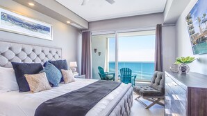 A modern hotel room with a large bed, a balcony with a view of the ocean, and a seating area with chairs. - Lovely 2 Bedroom Condominium (Puerto Peñasco)