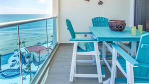 A balcony with turquoise chairs, a table, and a decorative bowl. - Lovely 2 Bedroom Condominium (Puerto Peñasco)