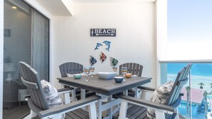 Ein Balkon mit Esstisch, Stühlen, Wandbild mit Fischen und einem Schild mit der Aufschrift 'BEACH'.