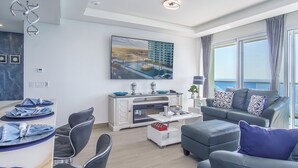 A modern living room with a large window, a fireplace, and a view of a building.