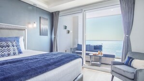 A modern hotel room with a bed, a seating area with a view, and a balcony with a table and drinks.