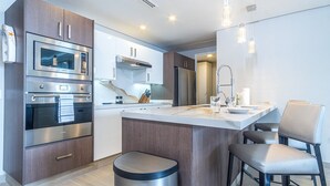 A modern kitchen with a central island, stainless steel appliances, and a minimalist design. - Amaizing Condo by the Beach Encantame W1704 (Puerto Peñasco)