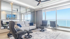 A modern living room with a sofa, two armchairs, a coffee table, and a view of the ocean through large windows. - Amaizing Condo by the Beach Encantame W1704 (Puerto Peñasco)