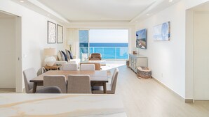 A spacious living room with a large dining table, a sofa, and a view of the ocean. - Sandy Paws 2 Bedroom 2 Bath Ocean Front Encantame Towers C1604 (Puerto Peñasco)