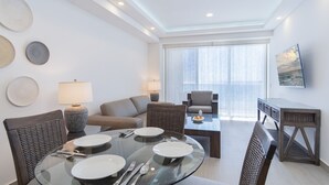 A modern hotel room with a dining area, a sofa, and a TV.