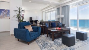 A modern living room with a blue sofa, a coffee table, and a view of the ocean.