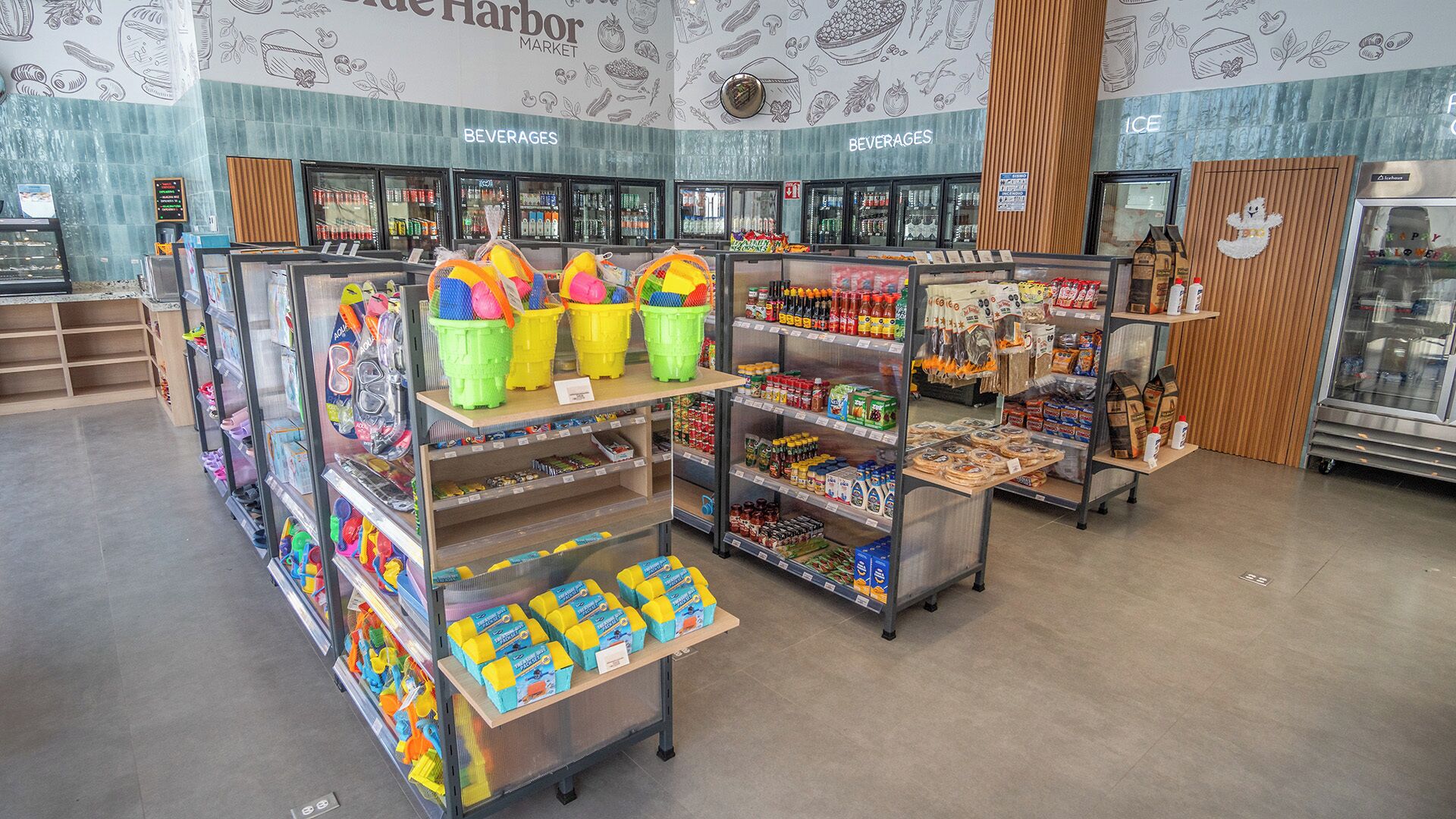 L'intérieur d'une épicerie, avec un rayon boissons et un rayon produits surgelés, des étagères remplies de divers produits et des paniers colorés exposés.