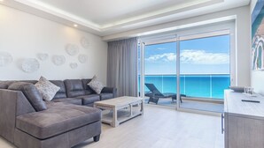 Ein modernes Wohnzimmer mit grauem Sofa, einem Couchtisch und Meerblick durch große Fenster.