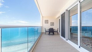 Un balcón con barandilla de cristal con vistas a la playa.